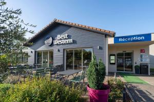 un restaurante con mesas y sillas frente a él en Best Western Bourgoin Jallieu, en Bourgoin