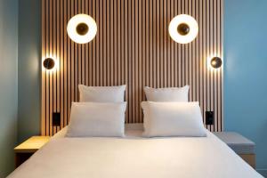 una camera con un letto bianco con due cuscini di Best Western Bourgoin Jallieu a Bourgoin