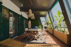 um pátio com uma mesa e cadeiras numa varanda em Surf GuestHouse - 7min walk to the beach em Pataias