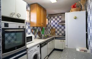 una cocina con armarios blancos y azulejos azules y blancos en Habitación doble con baño compartido en Benalmadena en Benalmádena