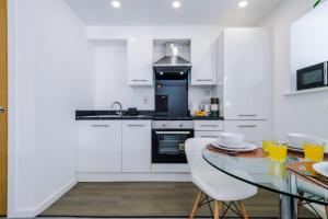a kitchen with white cabinets and a glass table at Westlea in Leeds +27 photos