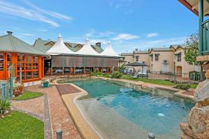 una piscina en un patio con un edificio en Haven- Lake Tinaroo Resort en Tinaroo