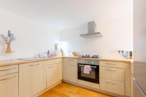 a kitchen with wooden cabinets and a stove top oven at Chic 1BD Maisonette wHot Tub King's Cross! in London