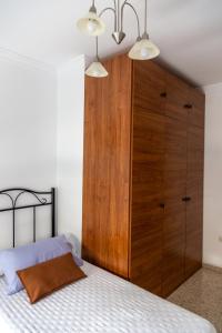 a bedroom with a bed with a large wooden cabinet at Apartamento San Miguel in Baena