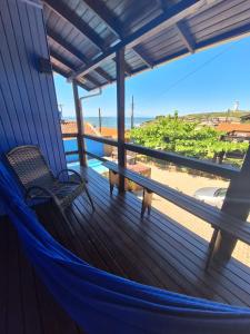a hammock on a porch with a view of the ocean at Pousada Kahuna Farol in Laguna