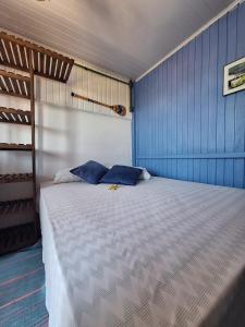 a bedroom with a large bed with blue walls at Pousada Kahuna Farol in Laguna