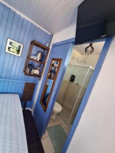 a blue room with a shower and a toilet at Pousada Kahuna Farol in Laguna