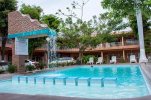 a swimming pool in front of a hotel with a fountain at Hotel La Quinta Posada Real in Culiacán