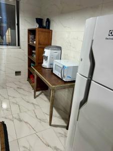 a kitchen with a table with a microwave and a refrigerator at Apartamento Apoteose Sambódromo in Rio de Janeiro