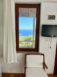 a room with a window and a chair and a television at Tsira Taş Otel in Döşeme