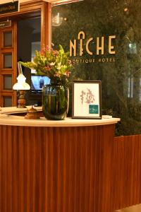 eine Theke mit einer Vase mit Blumen darauf in der Unterkunft Niche Boutique Hotel in Tirana