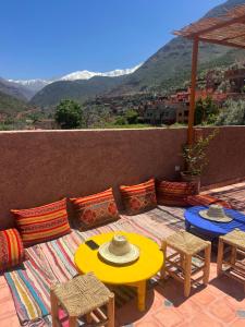 Tazart Lodge في مراكش: فناء بطاولة صفراء وكراسي وجبال