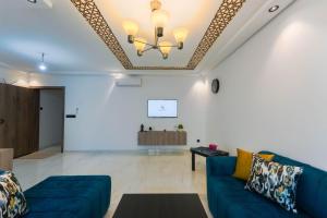 ein Wohnzimmer mit einem blauen Sofa und einer Decke in der Unterkunft Résidences & Suites Nador in Nador
