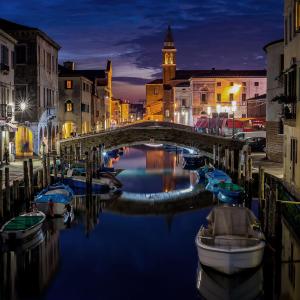 a bridge over a canal in a city at night at Venezia Beach in Chioggia