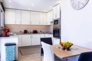 a kitchen with white cabinets and a wooden table with a bowl of fruit at OCEAN PANORAMA - 3 AC bedrooms, private garage, pool, 2 bathrooms, tv channels in Acantilado de los Gigantes +45 photos