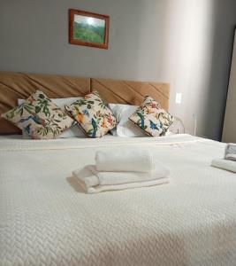 uma cama branca com almofadas e toalhas em CASA Próx Shopping Norte Londrina 2Qts Ar e CamaKing e Espacokids em Londrina