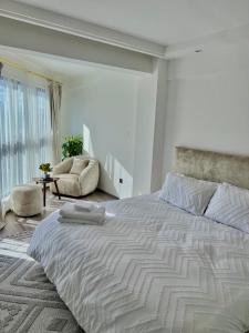 1 dormitorio blanco con 1 cama grande y 1 silla en RUYER LUXURY 1BR kileleshwa, en Nairobi