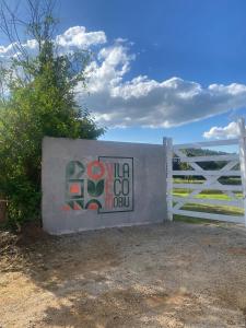 a white gate with a sign on it next to a fence at Vila Eco Mobili in São Roque