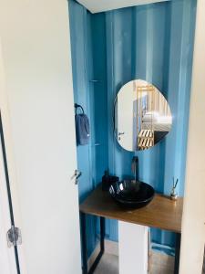 a blue bathroom with a black sink and a mirror at Vila Eco Mobili in São Roque