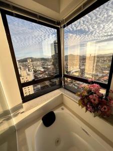 uma banheira na casa de banho com uma grande janela em Apartamento no centro, com vista mar e Cristo Luz em Balneário Camboriú
