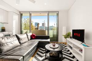 a living room with a couch and a tv at Central, modern 1 bedroom with air-con & balcony in Sydney