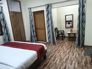1 dormitorio con cama, mesa y puerta en Corbett Rejoice Home Stay, en Jhirna