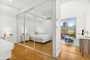 Habitación blanca con cama y pared de cristal en Central, modern 1 bedroom with air-con & balcony en Sídney