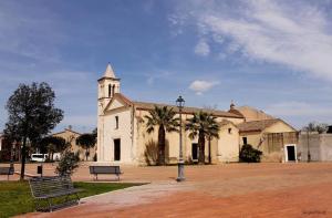 a building with a church with a clock tower at Aida Guest House - Decimomannu in Decimomannu