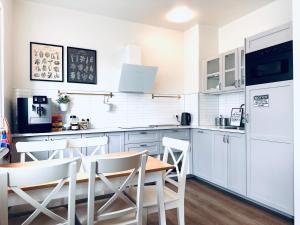 cocina con armarios blancos, mesa y sillas en Travel Inn, en Reikiavik