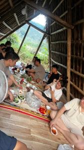 un grupo de personas sentadas alrededor de una mesa comiendo comida en Home 89 - Homestay & Retreat en Trai Ðỏ