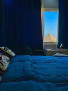 a blue bedroom with a bed and a window with a pyramid at Three pyramids view INN in Cairo