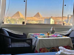 Three pyramids view INN في القاهرة: غرفة مع طاولة مطلة على الاهرامات