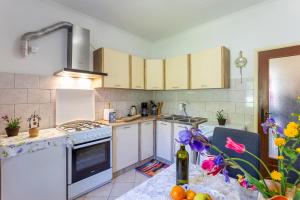 una cucina con elettrodomestici bianchi e un tavolo con fiori di Holiday house with a swimming pool Vinez, Labin - 22240 a Vinež