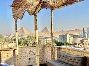 una sedia sotto un ombrellone su un balcone con piramidi di Three pyramids view INN a Il Cairo