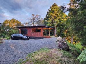 un'auto parcheggiata di fronte a una piccola casa di Rest and Relax a Karangahake