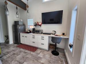 a kitchen with a desk with a television and a refrigerator at Tiny House with Hot Tub, close to golf, beaches and nature! in Oyster Bay