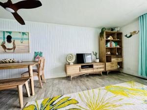 uma sala de estar com uma mesa e uma televisão em Beautiful Condo Right on the Beach em Hauula
