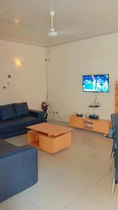 a living room with a couch and a table and a tv at Timba coquette-loge in Cotonou