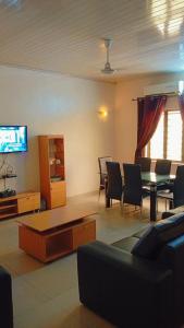 a living room with chairs and a table and a tv at Timba coquette-loge in Cotonou