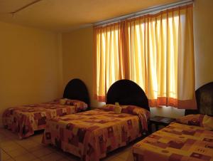ミナティトランにあるHotel Juarezのベッド2台、窓(カーテン付)が備わる客室です。