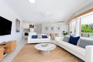 a living room with two white couches and a tv at Offshore Noosa Resort in Noosaville