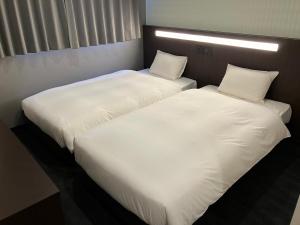 2 Betten nebeneinander in einem Zimmer in der Unterkunft ホテルジャパネスク京都駅 COTONE in Nishi-kujō-Toriiguchichō