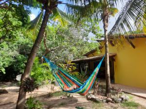 琵琶的住宿－Casa Cajueiro em Pipa，吊床挂在房子前面两棵棕榈树上