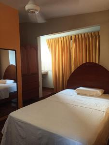 Schlafzimmer mit einem Bett, einem Spiegel und einem Fenster in der Unterkunft Cáyamahue Guest House in Pucallpa
