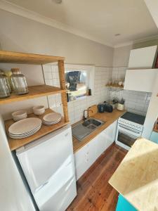 uma pequena cozinha com armários brancos e um lavatório em City Edge Nest em Wellington