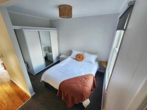 a small bedroom with a bed with an orange pillow at City Edge Nest in Wellington