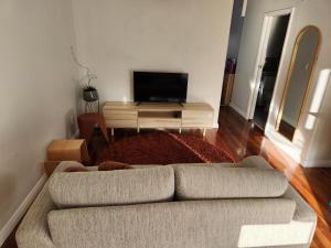 uma sala de estar com um sofá e uma televisão de ecrã plano em City Edge Nest em Wellington