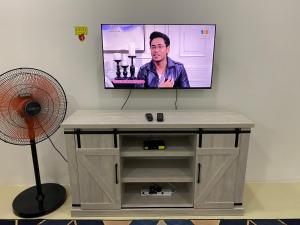 a flat screen tv on a wall with a fan at Homestay Cikgu Ahmed Batu Kikir in Batu Kikir