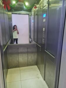 a woman taking a picture of a mirror in an elevator at Apartamento Recreio p12 in Rio de Janeiro