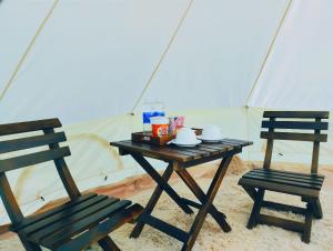 two chairs and a wooden table with a tent at Glamping Việt Úc in Kon Von Kla